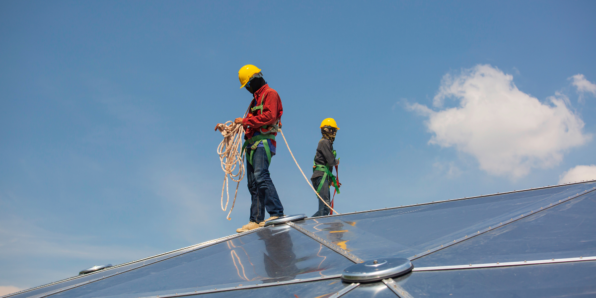 Two experienced traveling welders tied off on top of a geodesic dome 