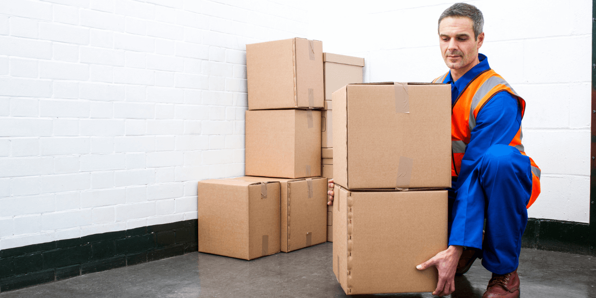 A worker lifting multiple boxes by using the correct lifting technique.